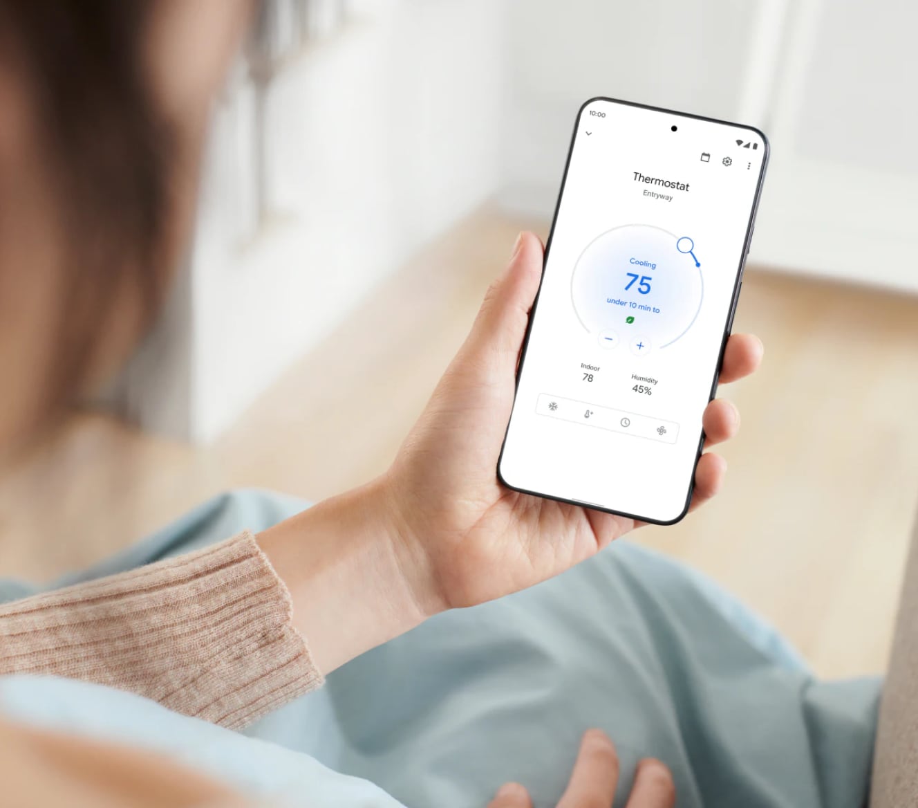 Woman adjusting her Google Nest Learning Thermostat using her cell phone