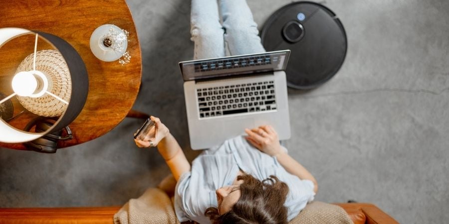 Woman in smart home sitting on couch with computer 